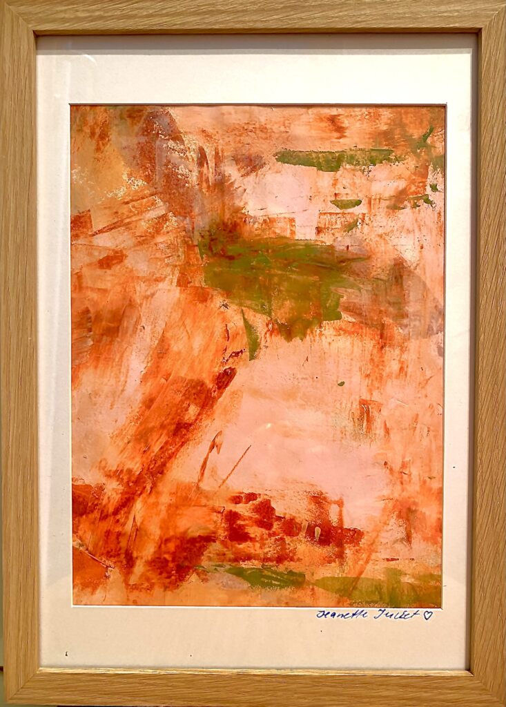 Abstrakt akrylmaleri Ro af Jeanette Juliet i varme orange, rosa og grønne nuancer, indrammet i en lys træramme.